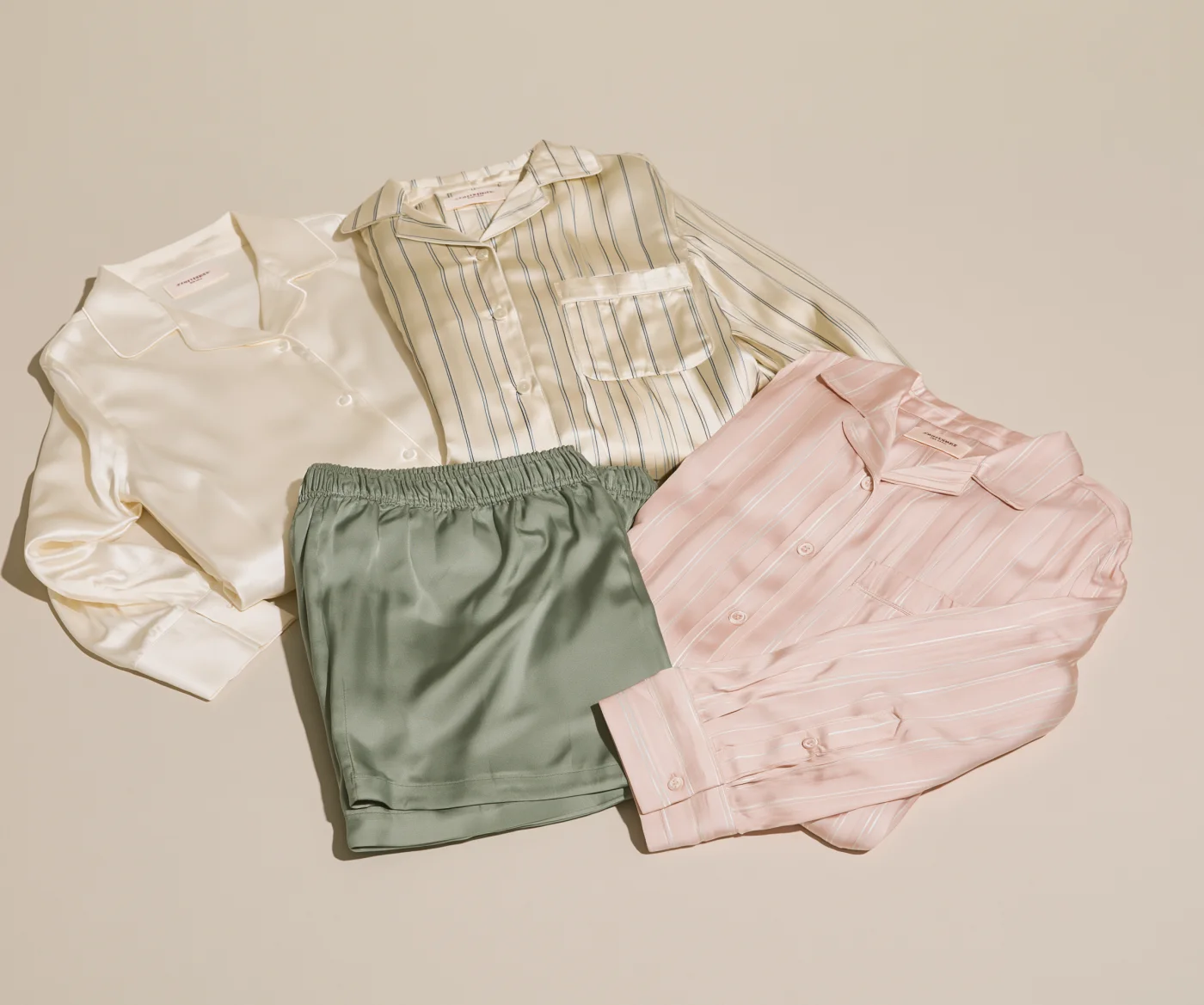 Flat lay of folded ivory, striped and blush pajama sets for custom product development